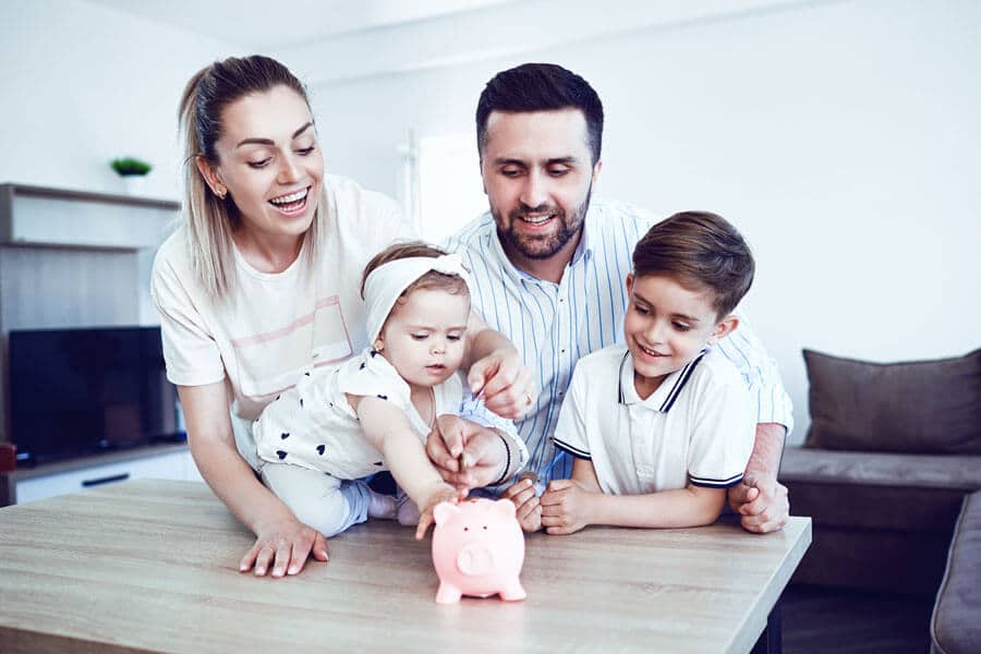 Eine glückliche Familie, die Geld in ein Sparschwein steckt