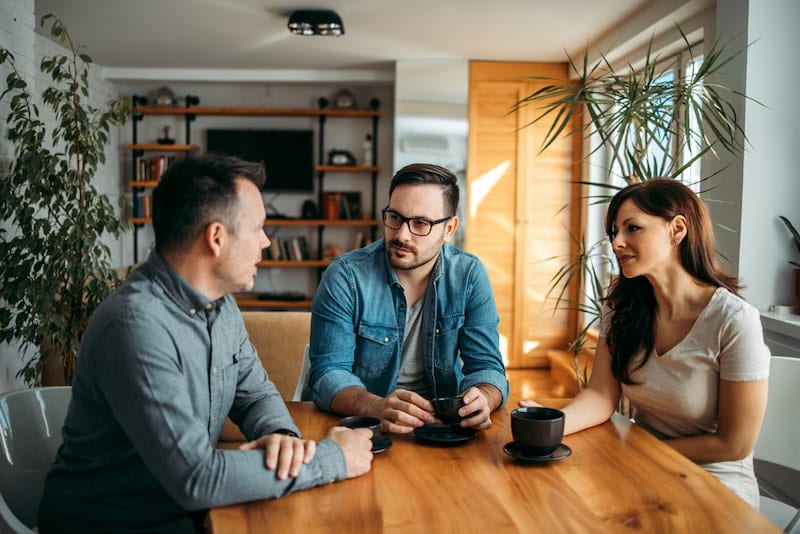 Ein Paar berät sich mit einem Makler, es will eine vermietete Wohnung verkaufen