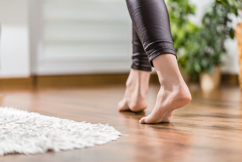 Eine Frau geht ohne Schuhe auf dem Boden mit einer Fußbodenheizung