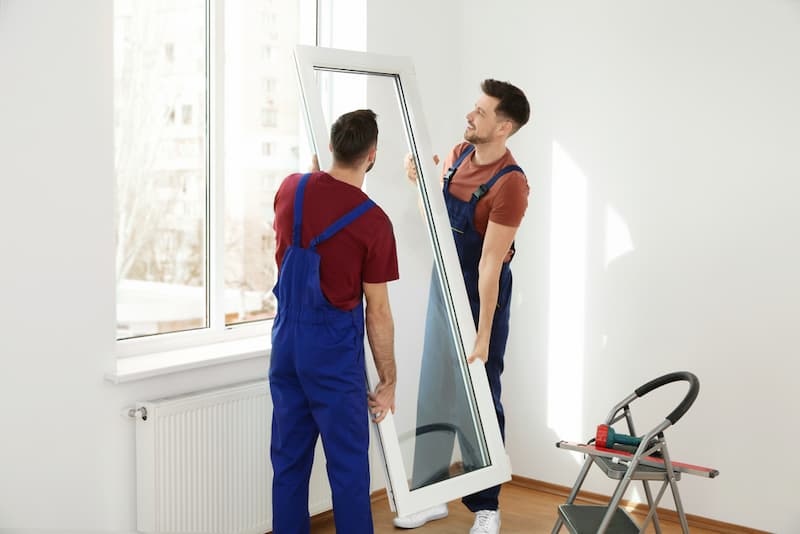 Zwei Männer bauen neue Fenster ein, dafür gibt es einen Modernisierungskredit