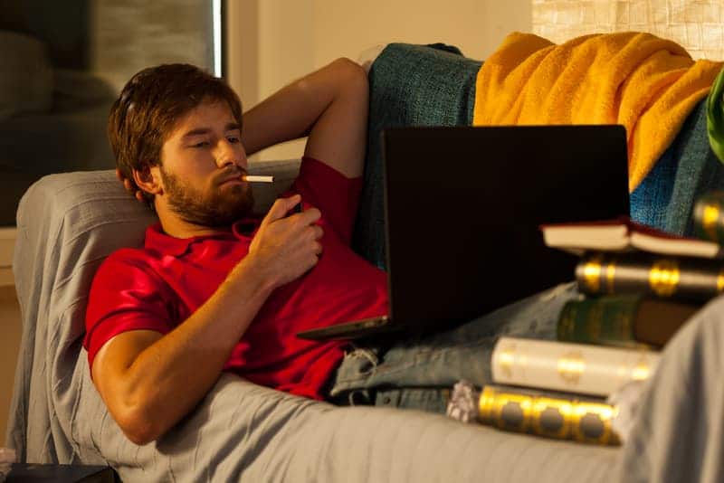 Ein Mann liegt auf dem Sofa und raucht in der Wohnung